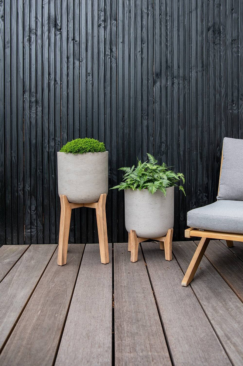 two sizes of Grey Charlie Pot on Stand by Pottery Pots on a deck in front of a black slatted wood wall. 