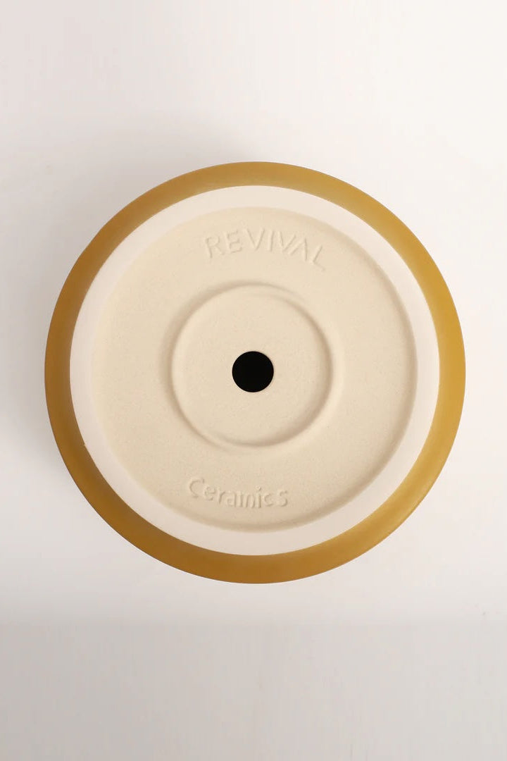 The bottom of a yellow planter showing the drain hole ©LBE Design