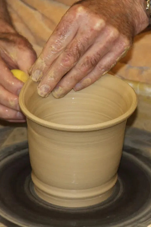 Person shaping a clay pot on a pottery wheel at Bruning Pottery ©Bruning Pottery