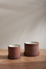 Two sizes of Salamanca pots empty and sitting on a wood table. 