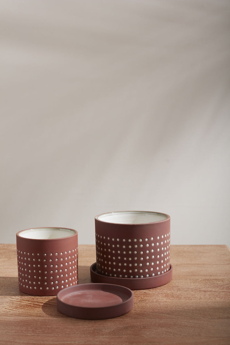 Two different sizes of Salamanca pots with the smaller one's saucer off and in front. 