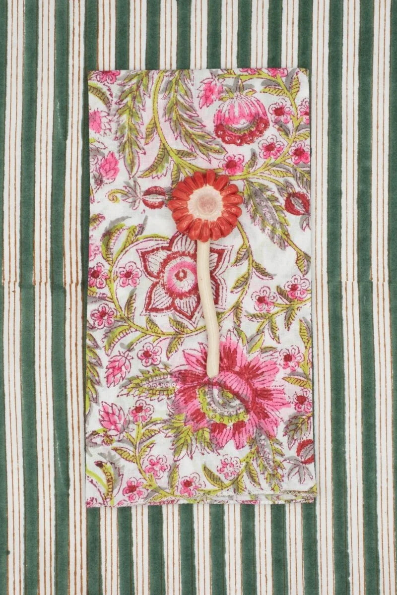 Cotton Napkins Gypsophil Pasteque sitting on a green striped surface and a flower on top ©Suzette a Table