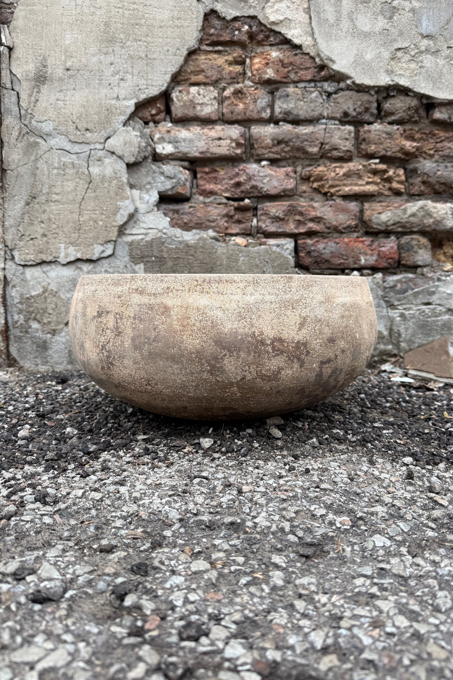Sansui Tapered Vietnamese Rustic Bowl Large on a stone floor with a rustic wall in the background ©Sprout Home