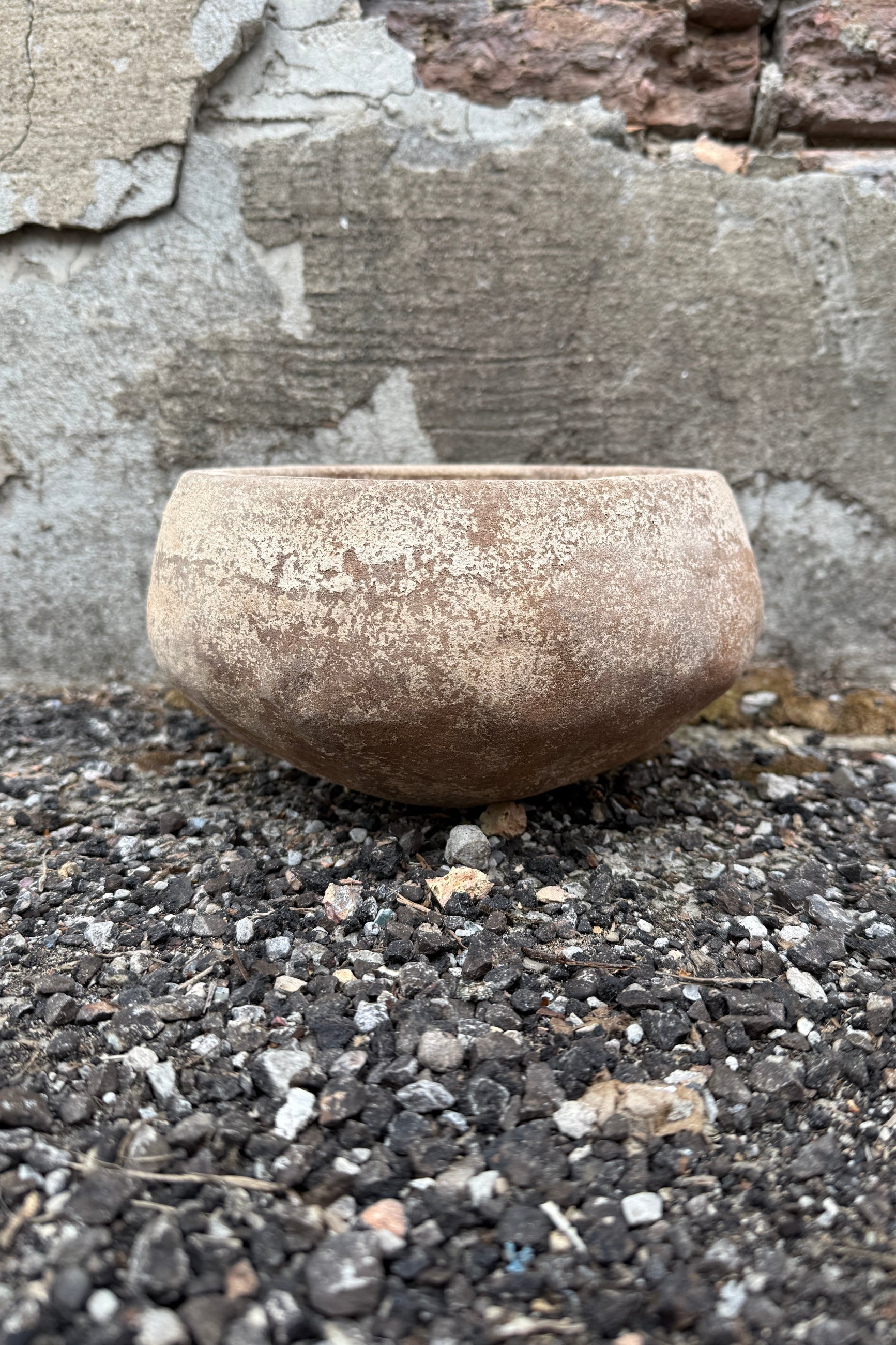 Stone Sansui Tapered Vietnamese Rustic Small bowl on a gravel surface with a stone wall background ©Sprout Home