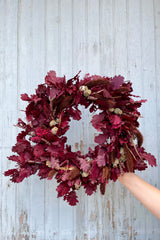 Quercus ruby wreath being held against a barn wall