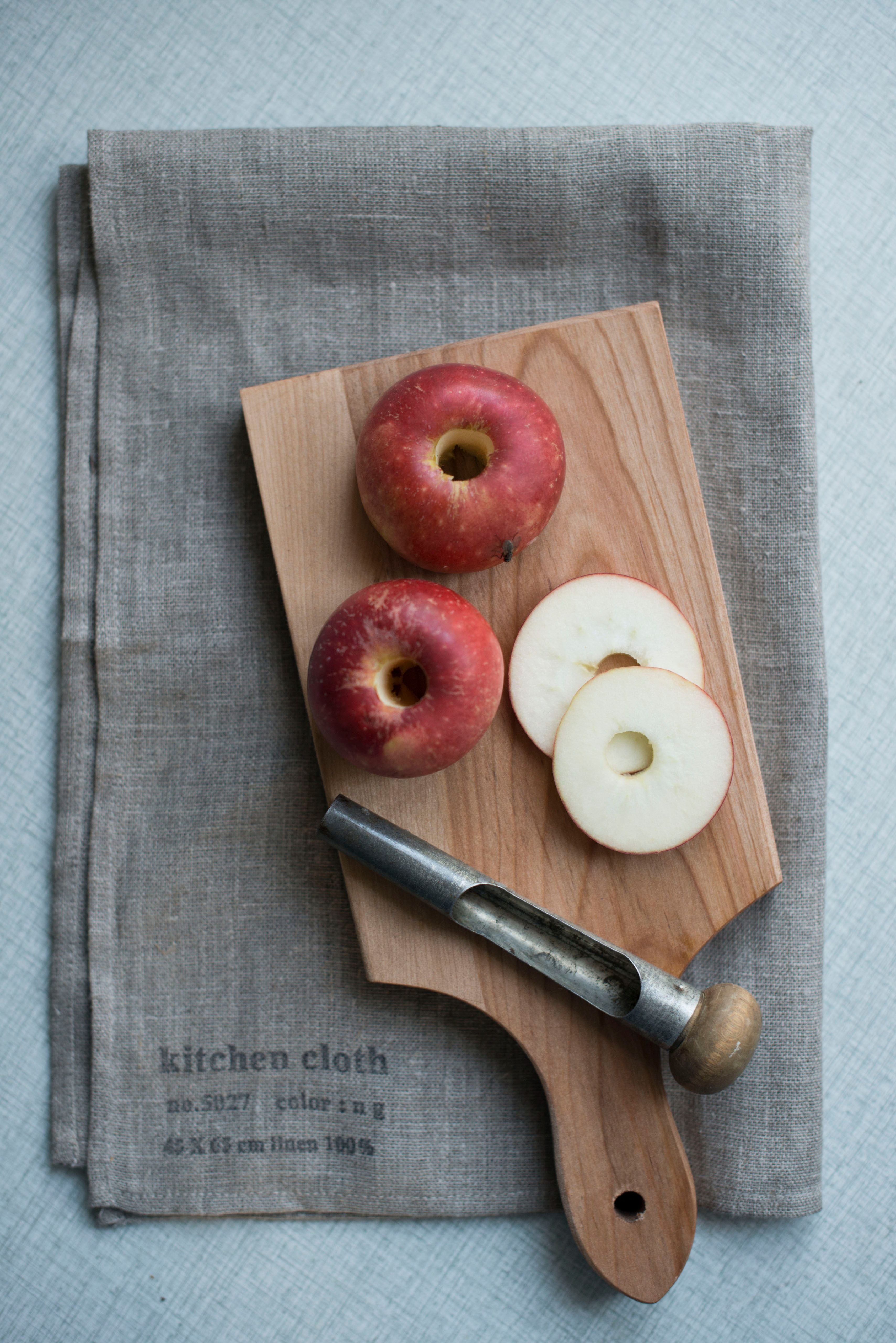 The natural Linen Kitchen Cloth by Fog Linen Work folded and flat with a cutting board and apples sitting on top