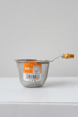 Stainless steel tea strainer by Miya sits on a white surface in a white room