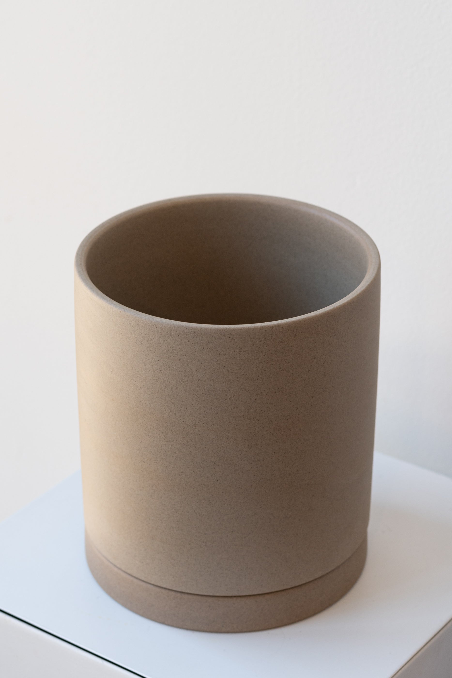 Sand large Sekki plant pot by Ferm Living on a white pedestal in front of a white background
