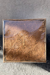 A compressed bale of Orchid coir against a grey wall.