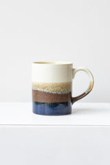 Cafe Con Panna Mug by Kotobuki sits on a white surface in a white room