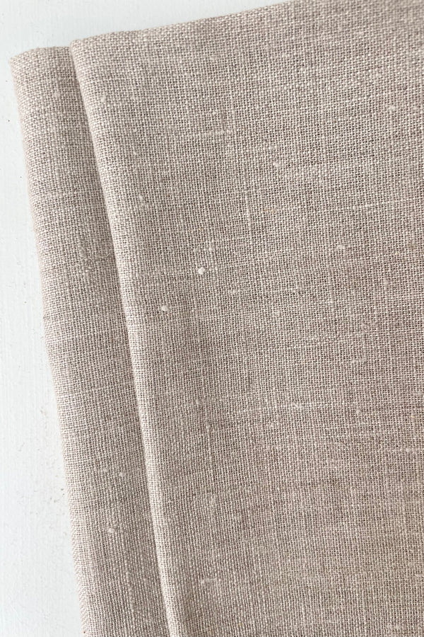 detail of Civil Alchemy Natural linen towel held in front of white background