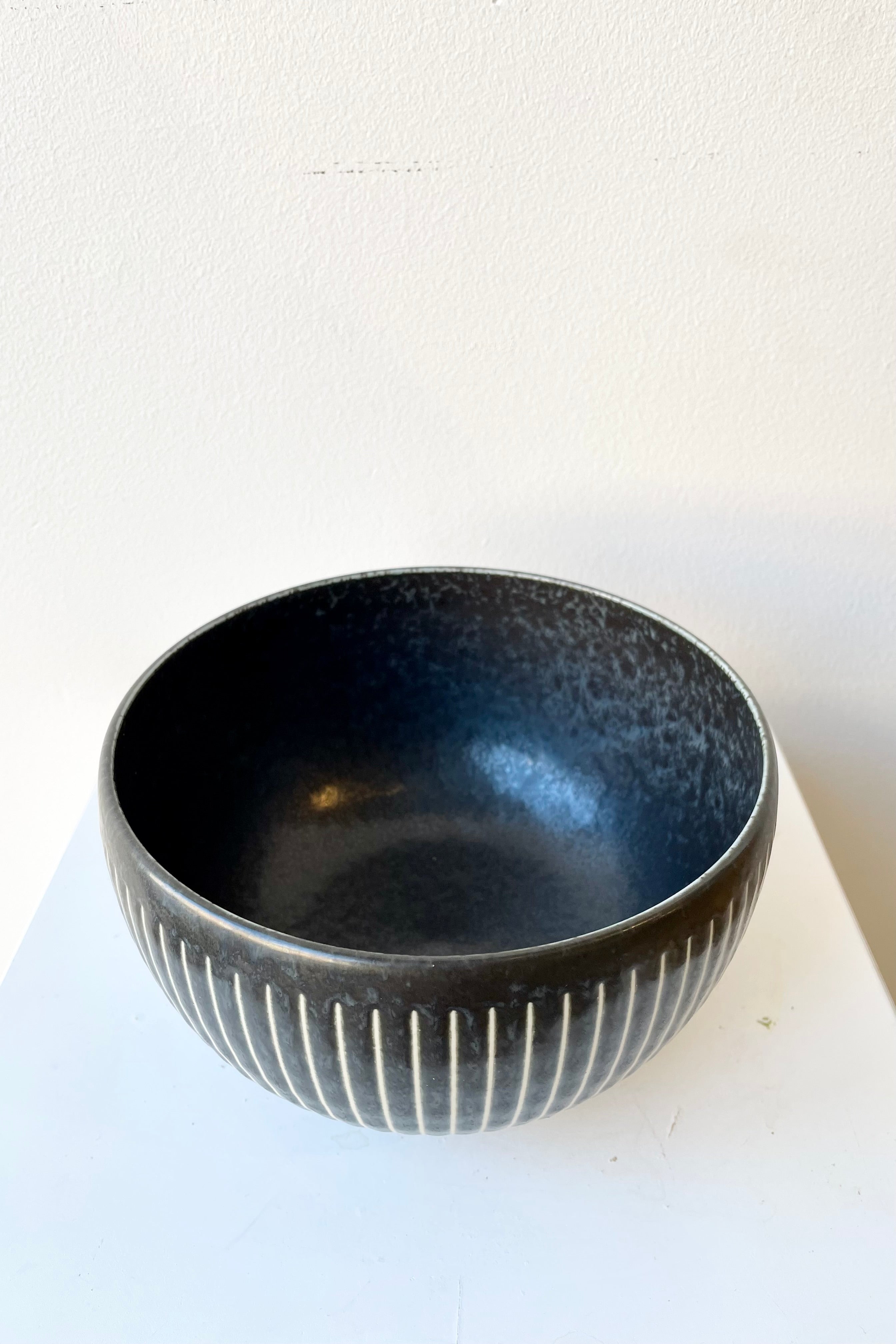 The Black Horsetails Bowl extra large against a white wall at Sprout Home.