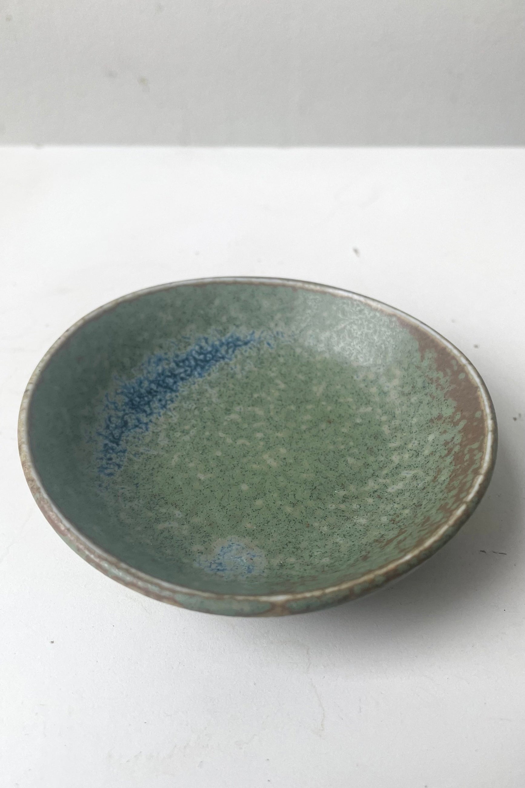 An overhead view of Sauce dish terra green against white backdrop  ©Sprout Home