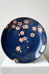 The 10" Namako Pink Sakura plate shown from above against a white wall. 