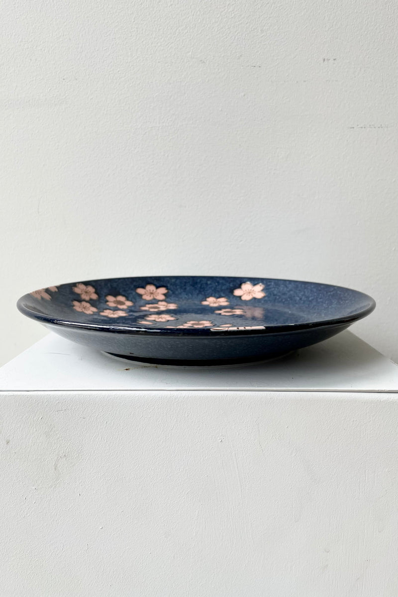 The 10" Namako Pink Sakura plate shown from the side against a white wall.