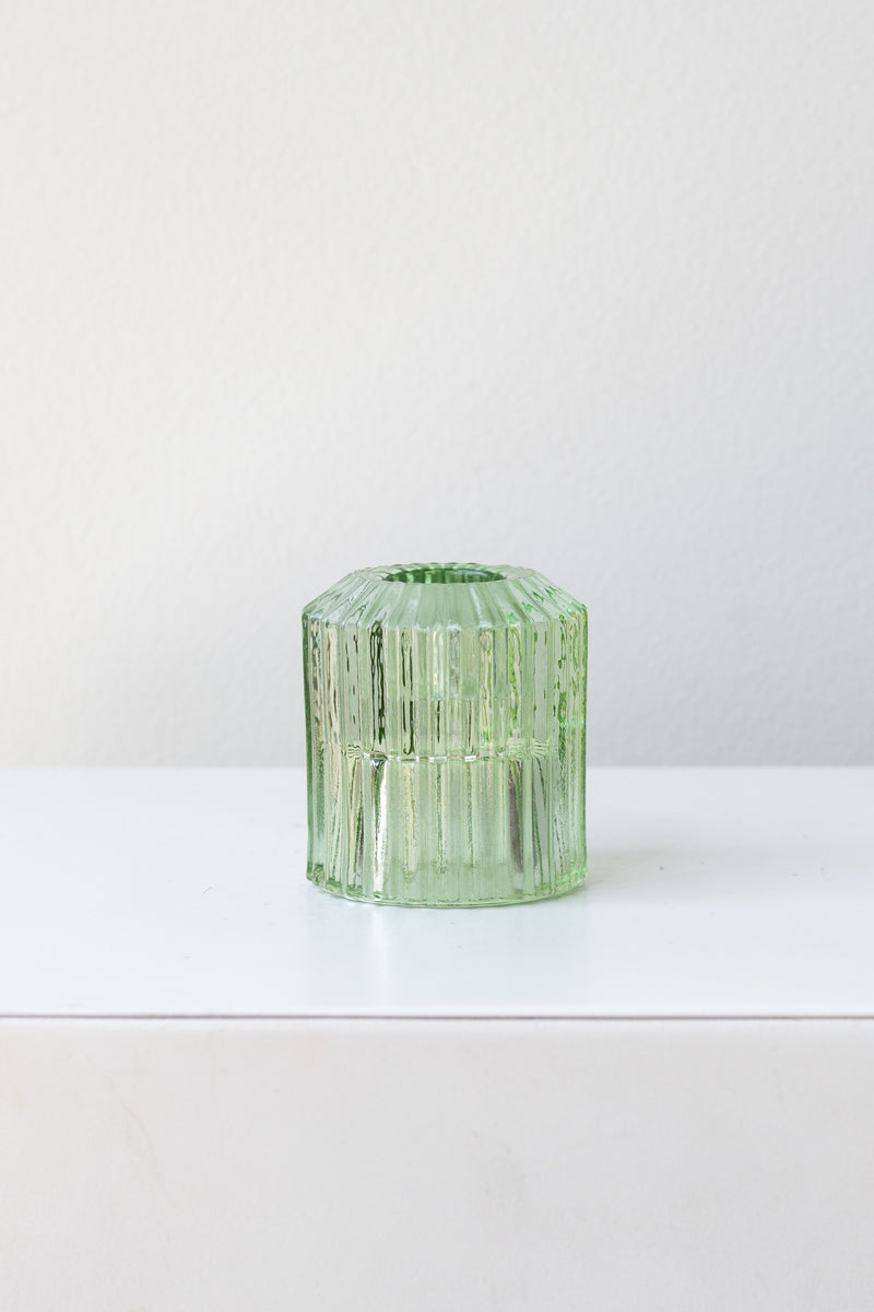 Green pleated glass candle holder in front of white background