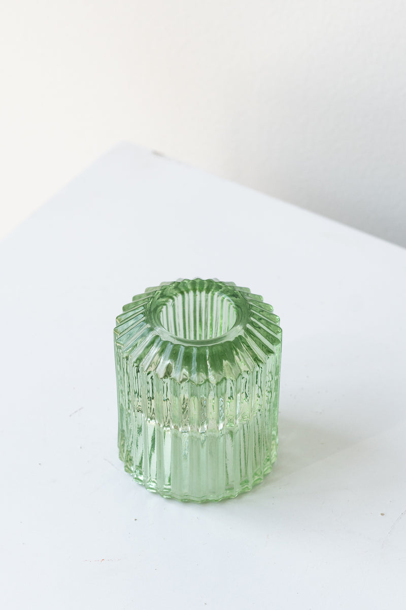Green pleated glass candle holder in front of white background