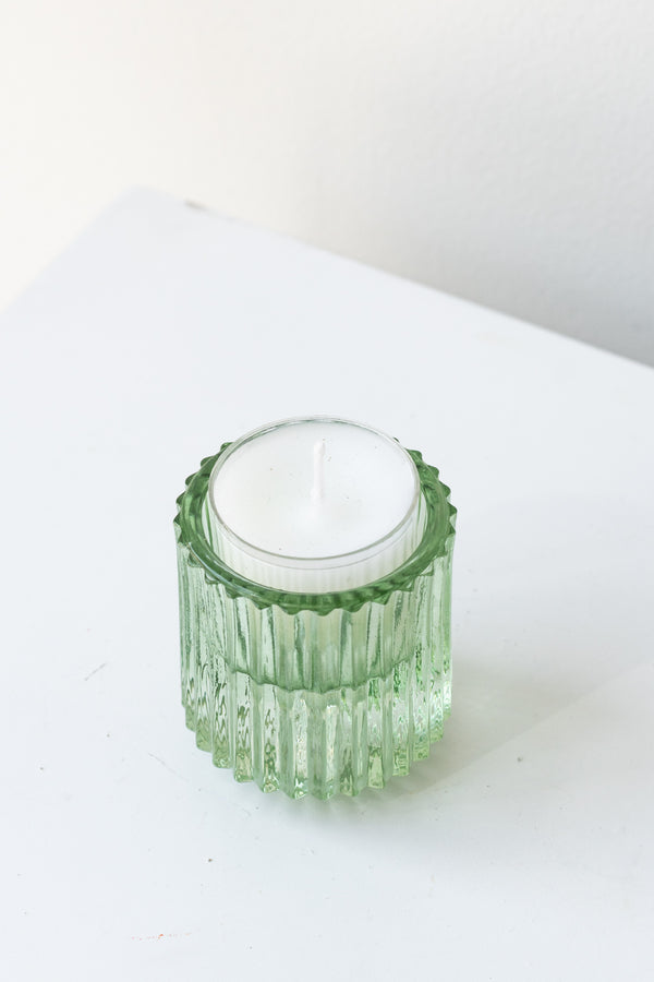 White tea light candle in green pleated glass candle holder