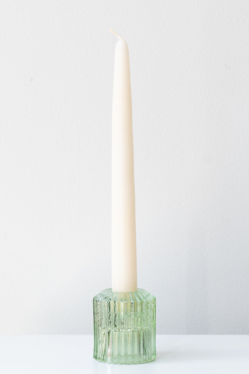 White taper candle in green pleated glass candle holder