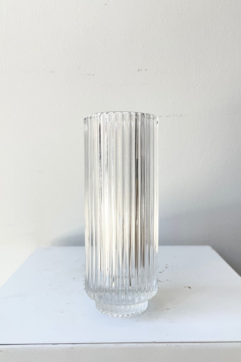 The 6 1/4" pleated clear glass vase against a white wall at Sprout Home. 