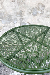An overhead detailed view of the 23.75" Martini Iron Round Bistro Table in Moss against a concrete backdrop 