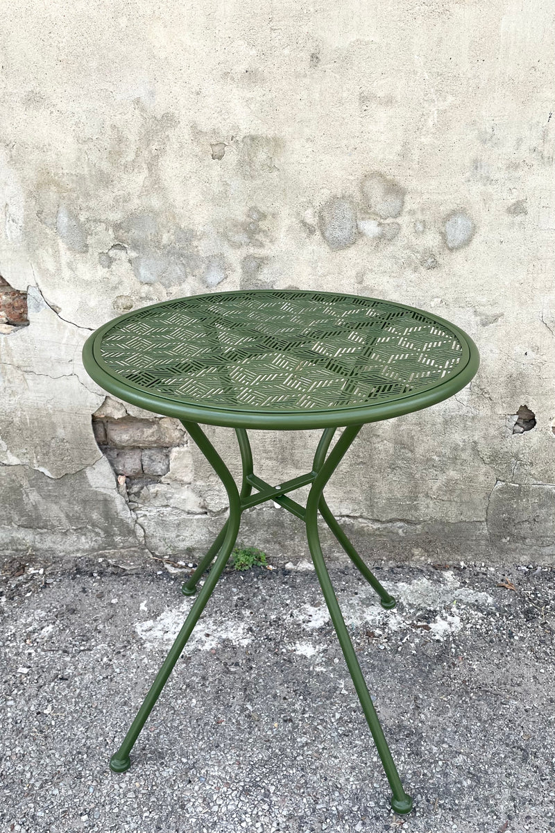 A frontal view of the 23.75" Martini Round Bistro Table in Moss against a concrete backdrop