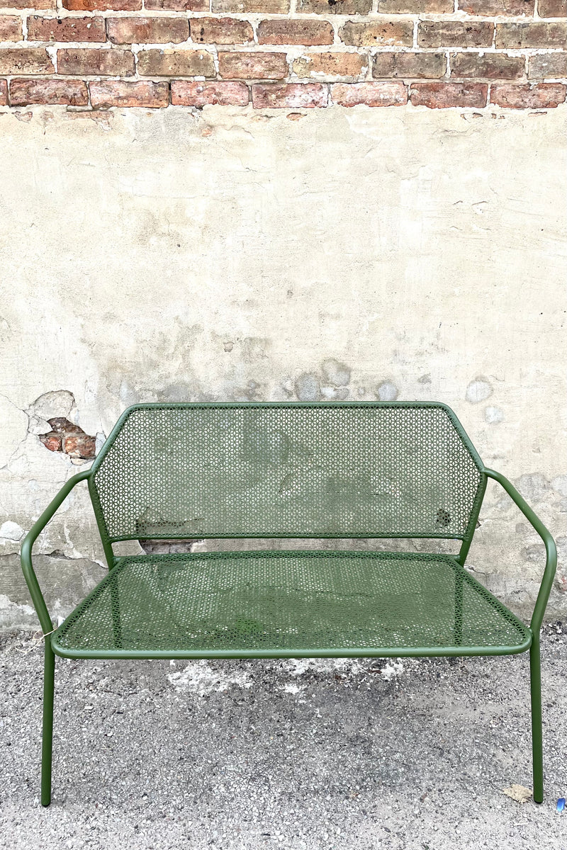 A frontal view of the Martini Iron Garden Bench in Moss against a concrete backdrop