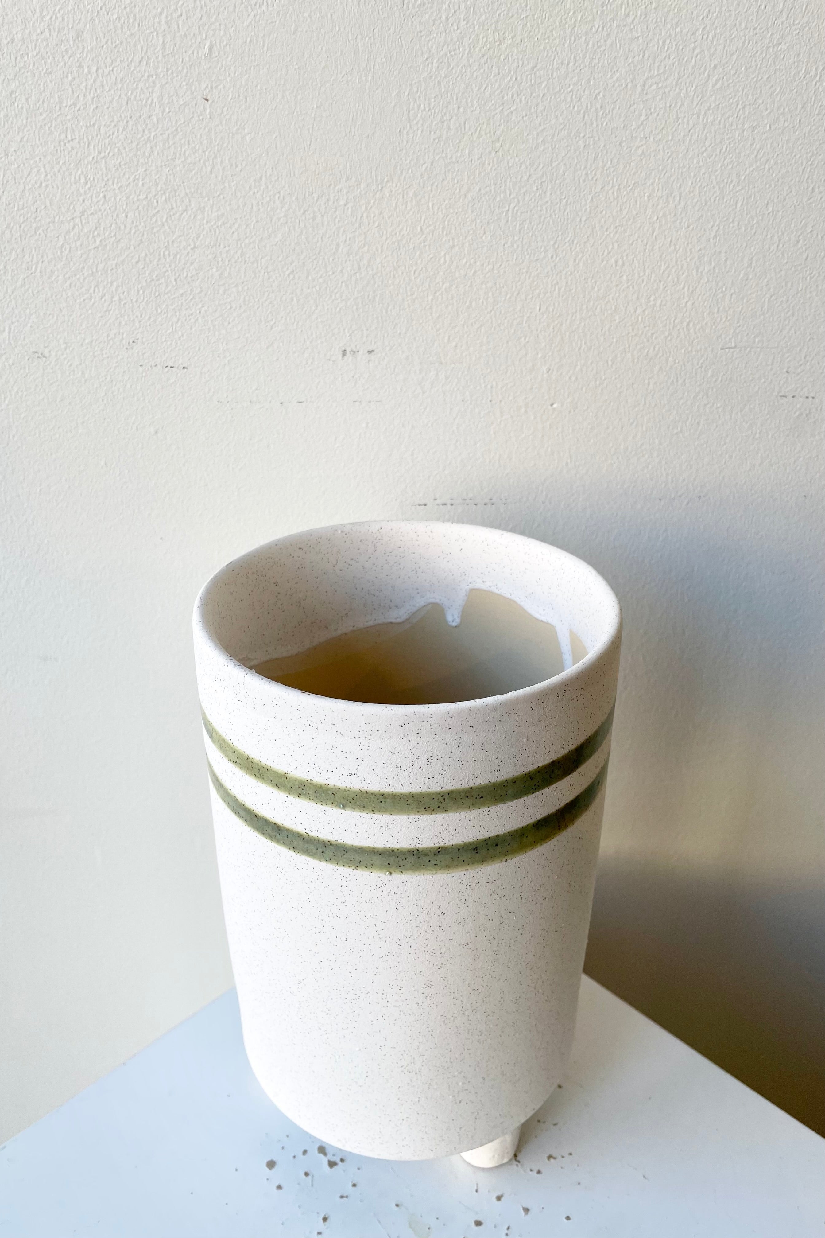 The tall teal and white fluorite ceramic cachepot showing its two horizontal stripes at Sprout Home.