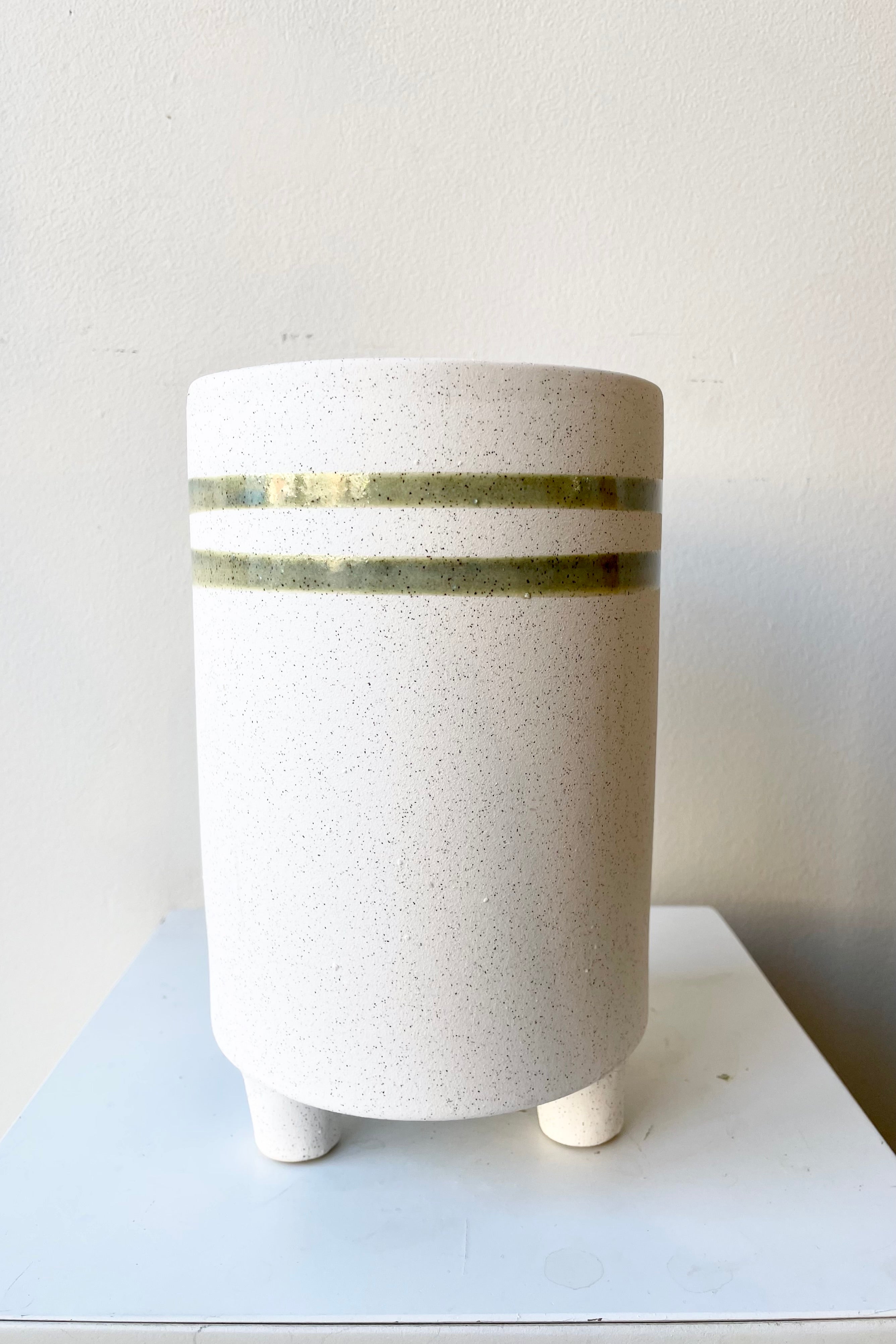 The tall teal and white fluorite ceramic cachepot showing its two horizontal stripes at Sprout Home.