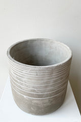 The Paso linear cement cachepot against a white wall and showing part of the inside of the pot at Sprout Home.