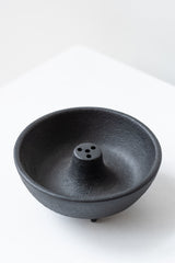 Black cast iron incense weight by Kotobuki sits on a white surface in a white room