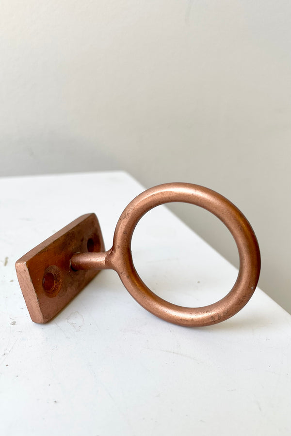 The Copper Bijou hanging ring on a white platform at Sprout Home.