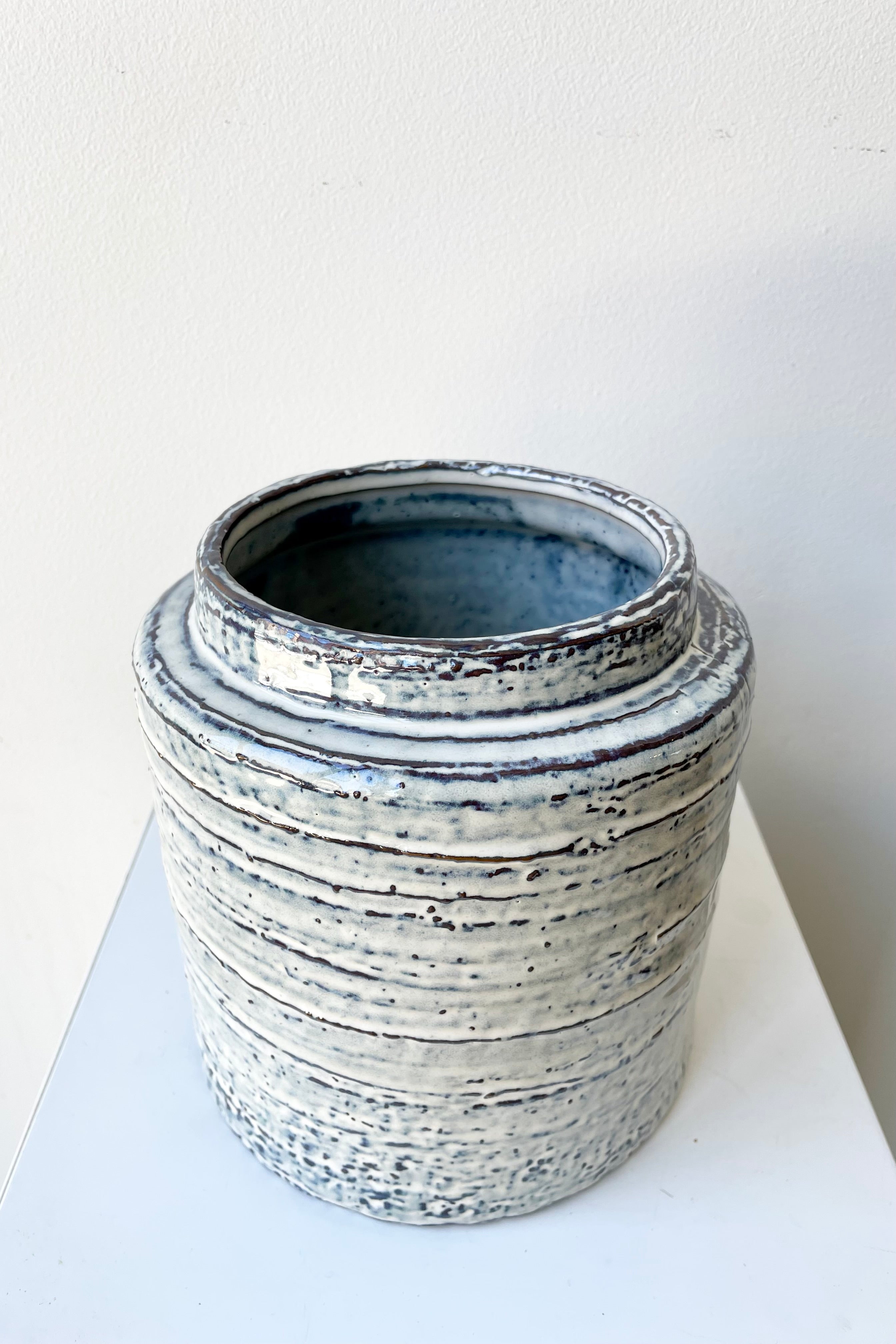 The Toku Crock showing its indigo and off white patterns against a white wall at Sprout Home.