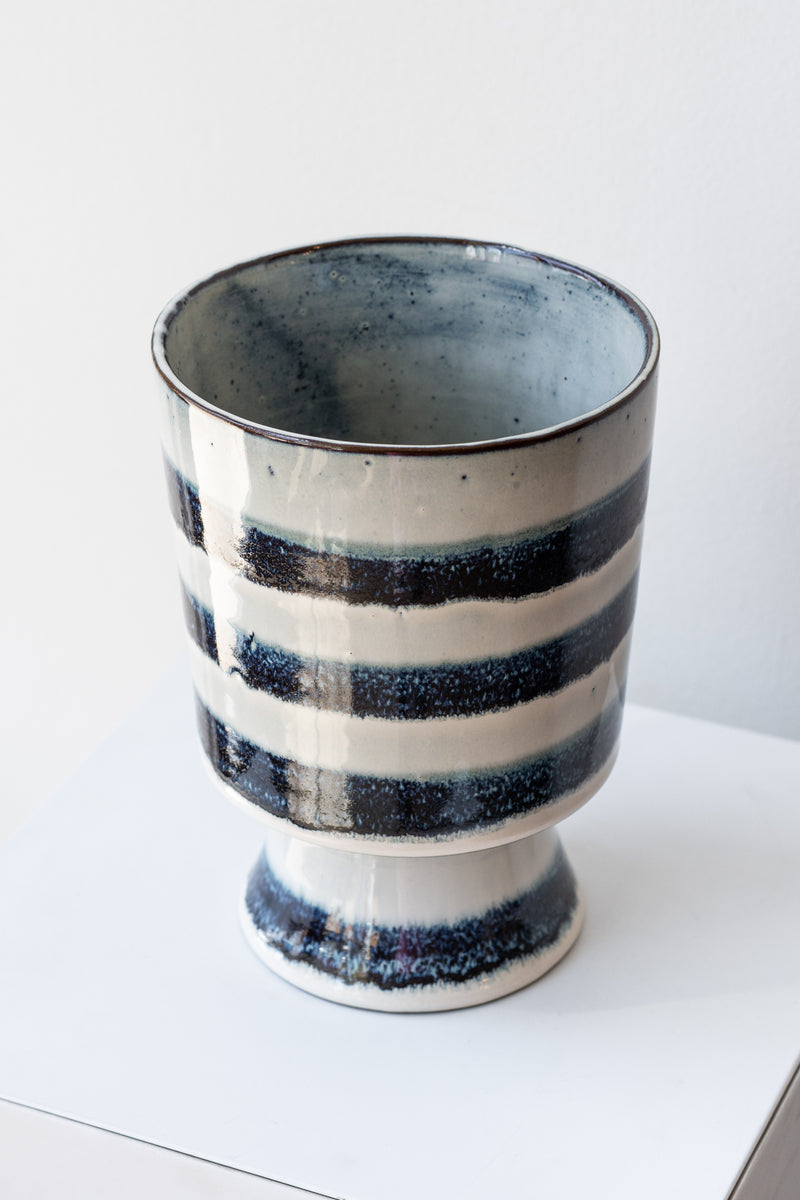 Striped blue and white glazed Toku chalice vase by Homart on a white surface in a white room