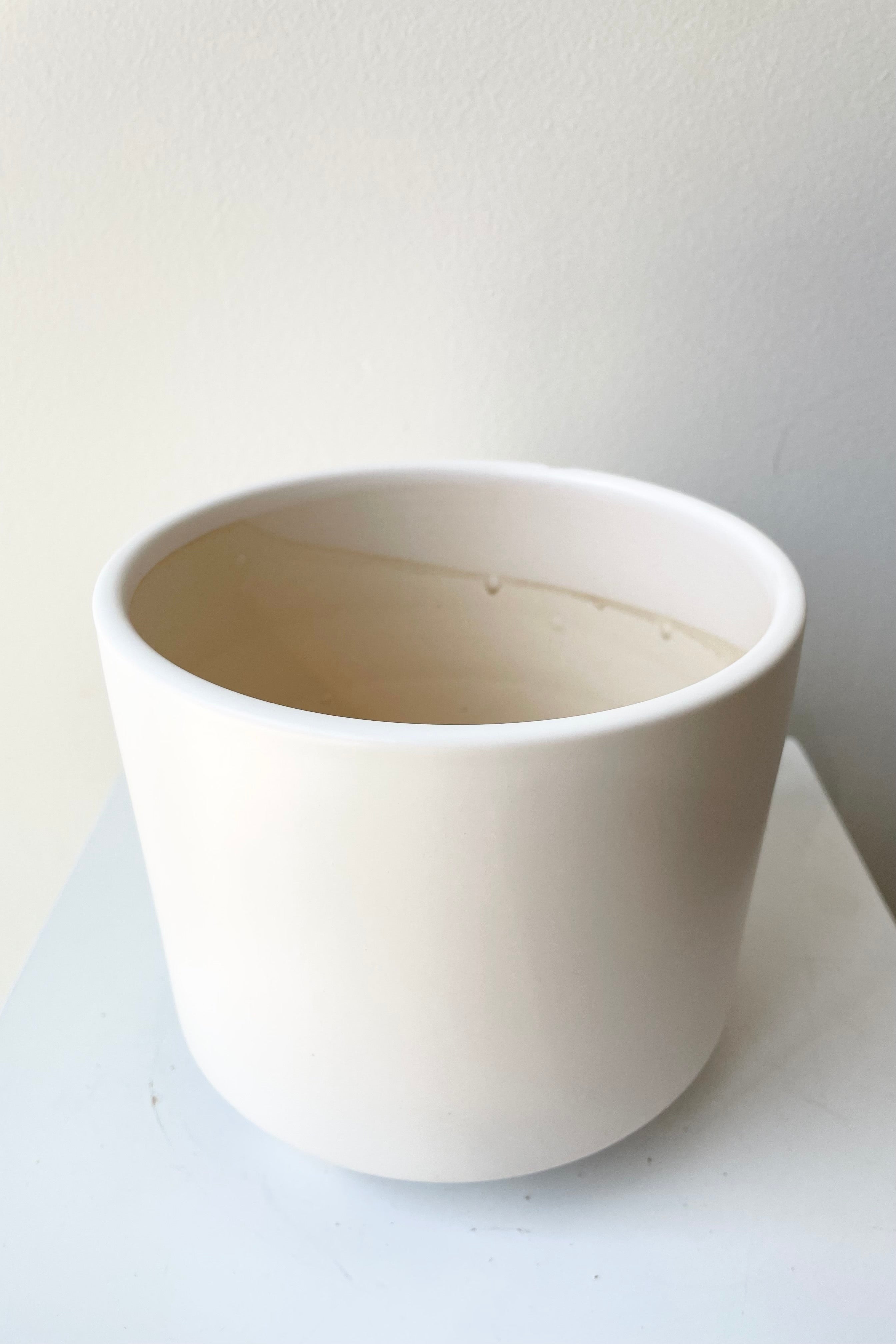 The white Simon footed pot small against a white wall at Sprout Home.