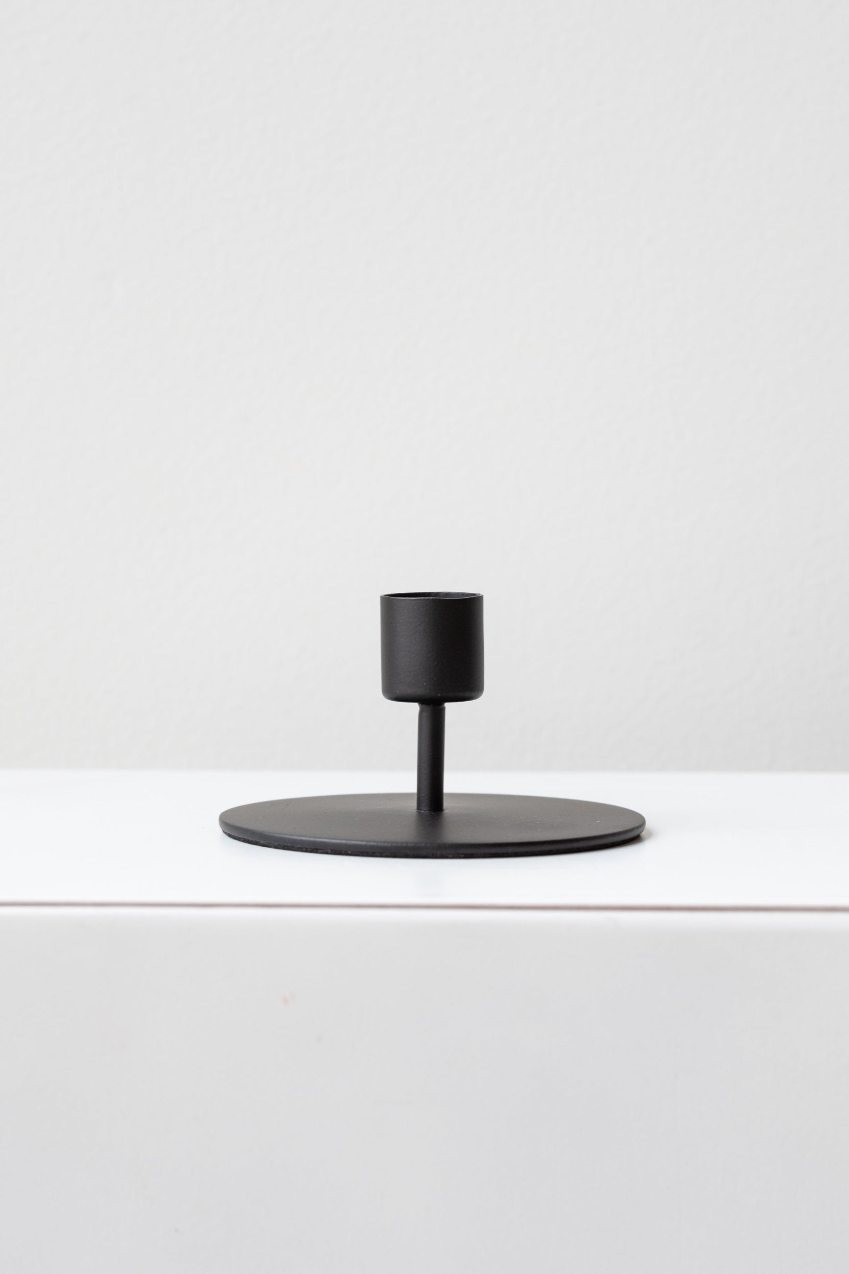 A sleek, minimalistic matte black finish taper candle holder on a white surface. ©Sprout Home