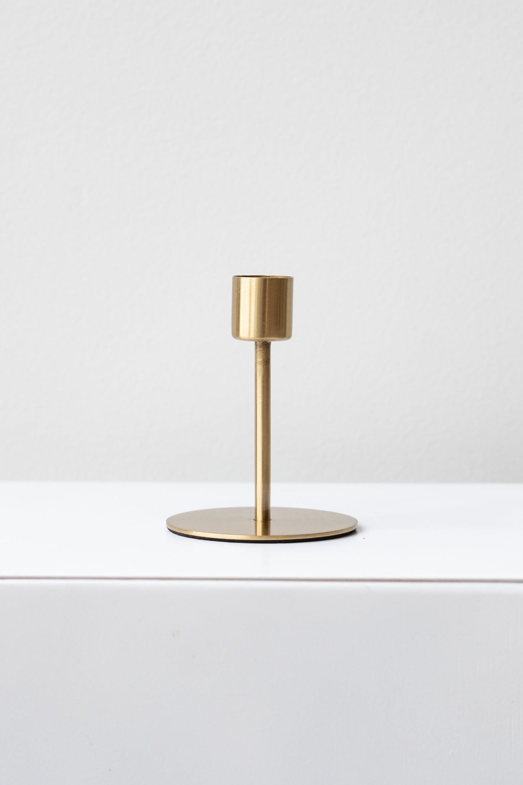 A simple, elegant gold-colored metal taper candle holder with a sleek silhouette. ©Sprout Home