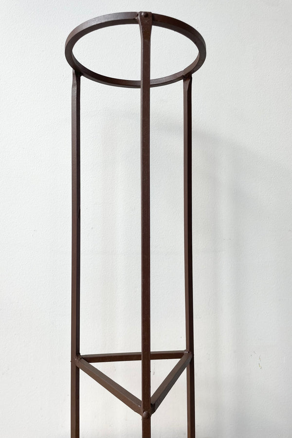 detail of Iron Plant Stand Medium 8"dia x 26.5"H against a white wall