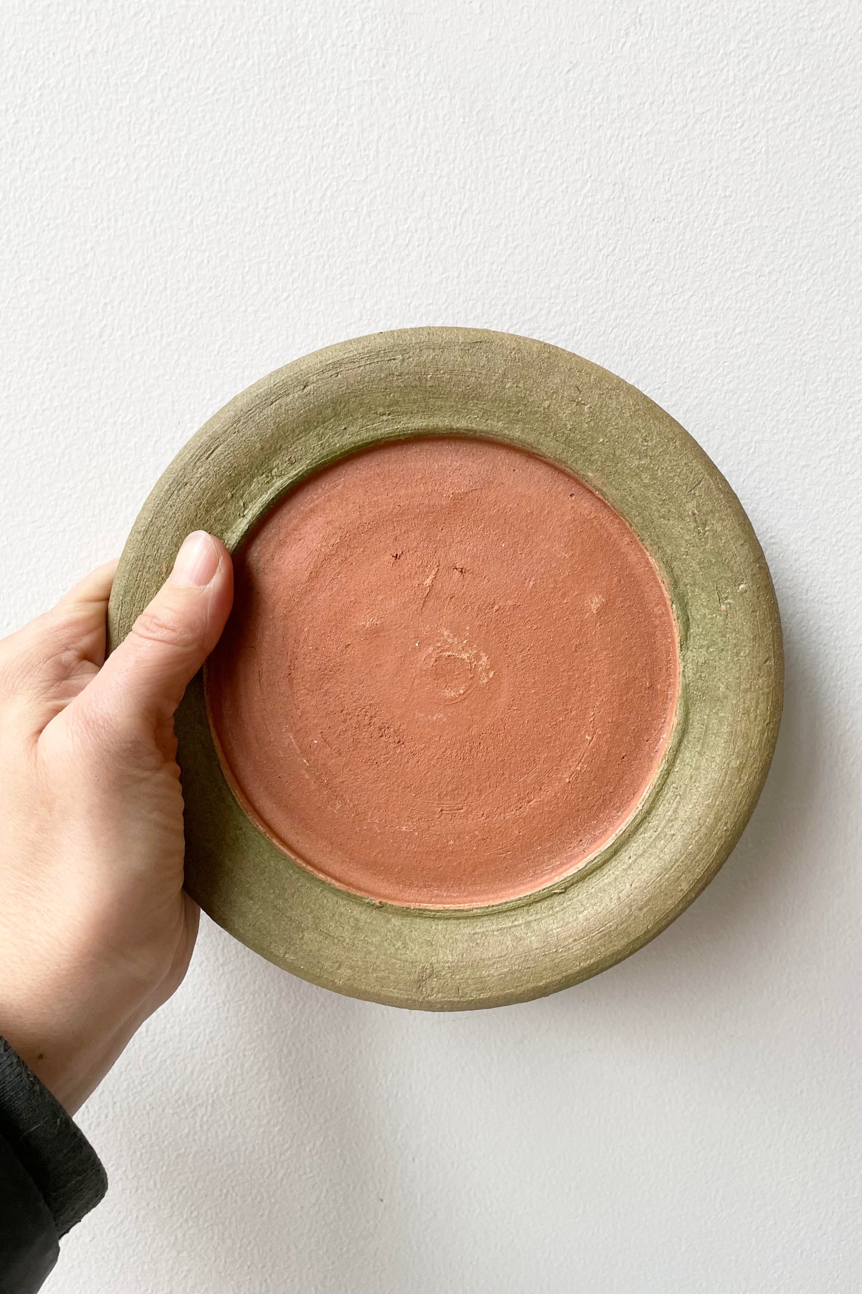 A hand holds the Aged Saucer #2 against a white backdrop.  ©Sprout Home