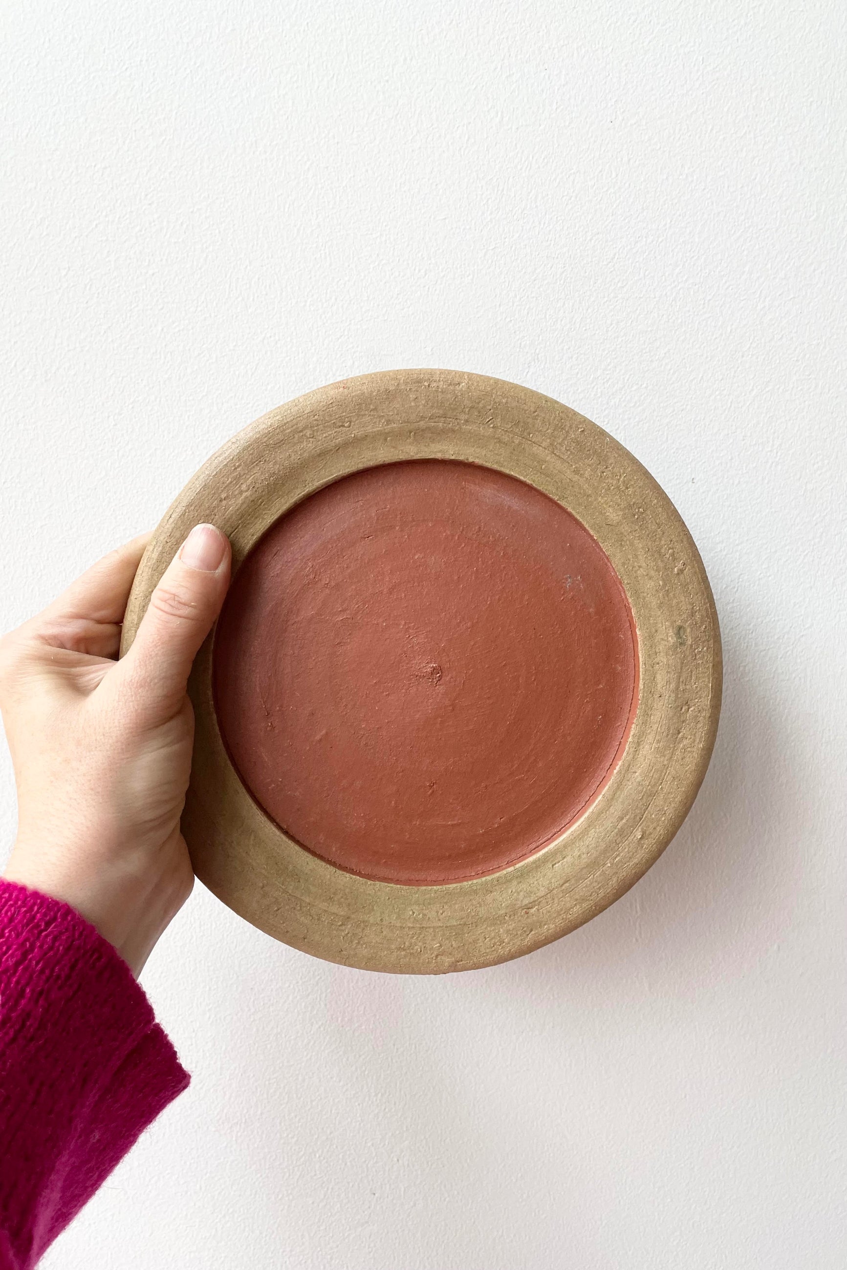 A hand holds the Aged Saucer #3 against a white backdrop.   ©Sprout Home