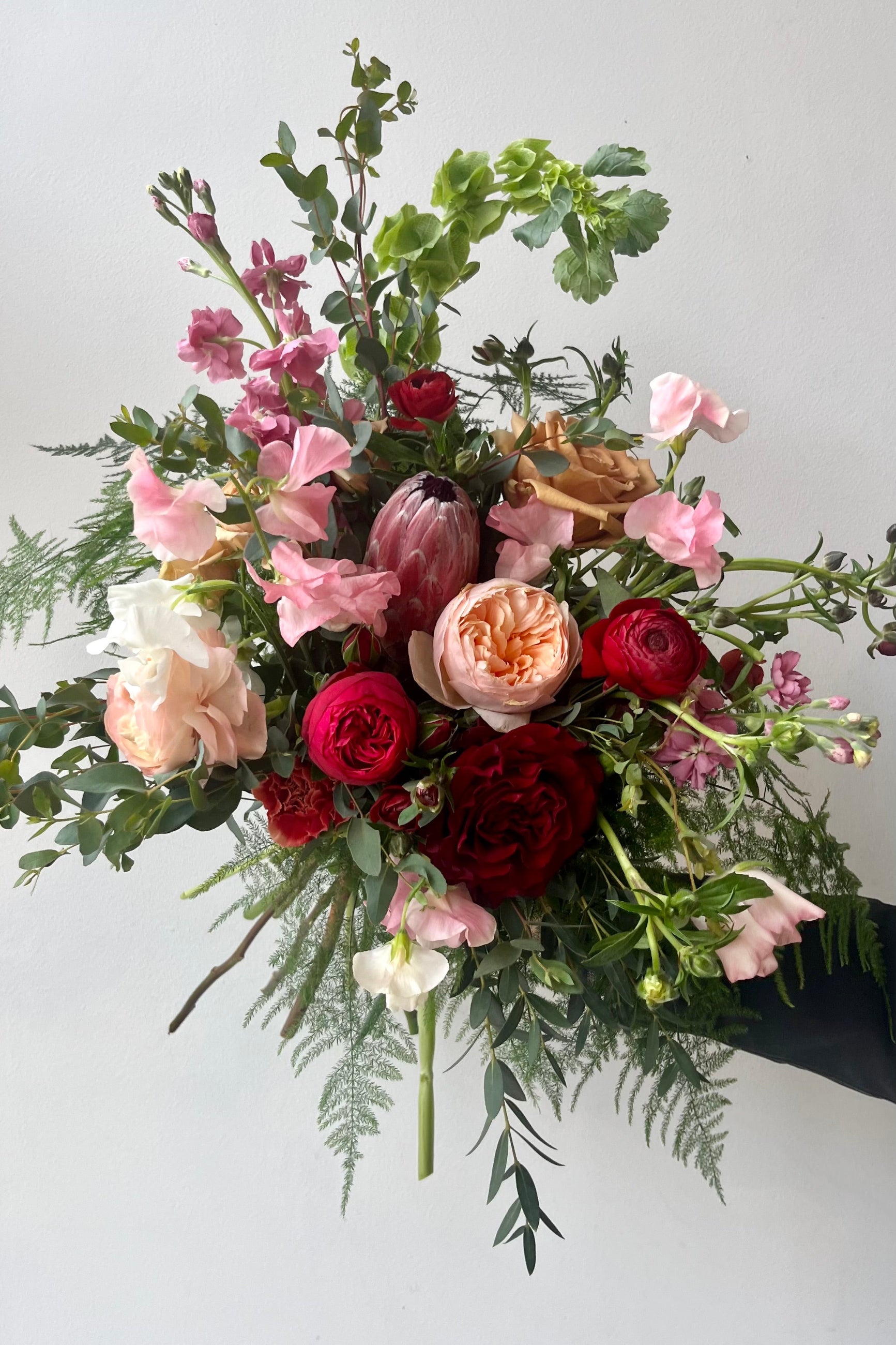 A hand holds an example of fresh Floral Arrangement Modern Love from Sprout Home Floral in Chicago for Valentine's Day ©Sprout Home #size_$160