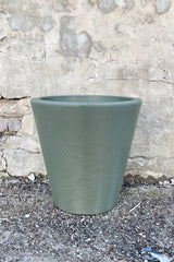 The 16" olive Madison planter against a concrete wall. 