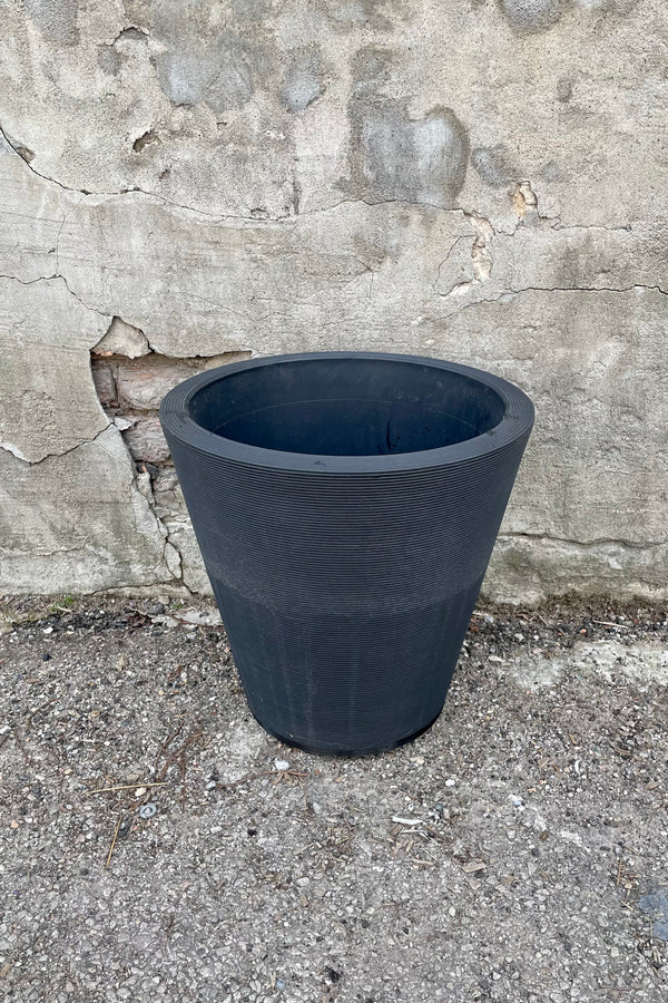 The 16" caviar black Madison pot against a concrete wall. 