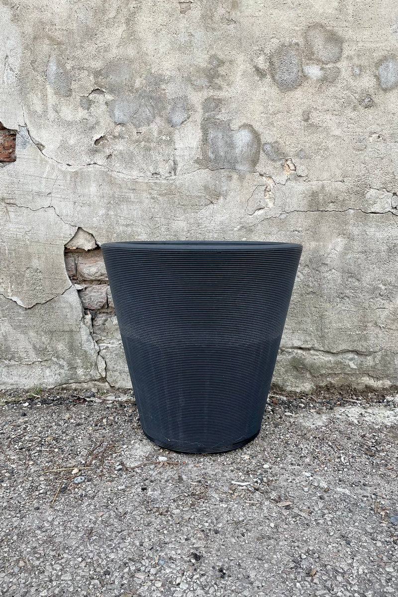 The 16" caviar black Madison pot against a concrete wall. 