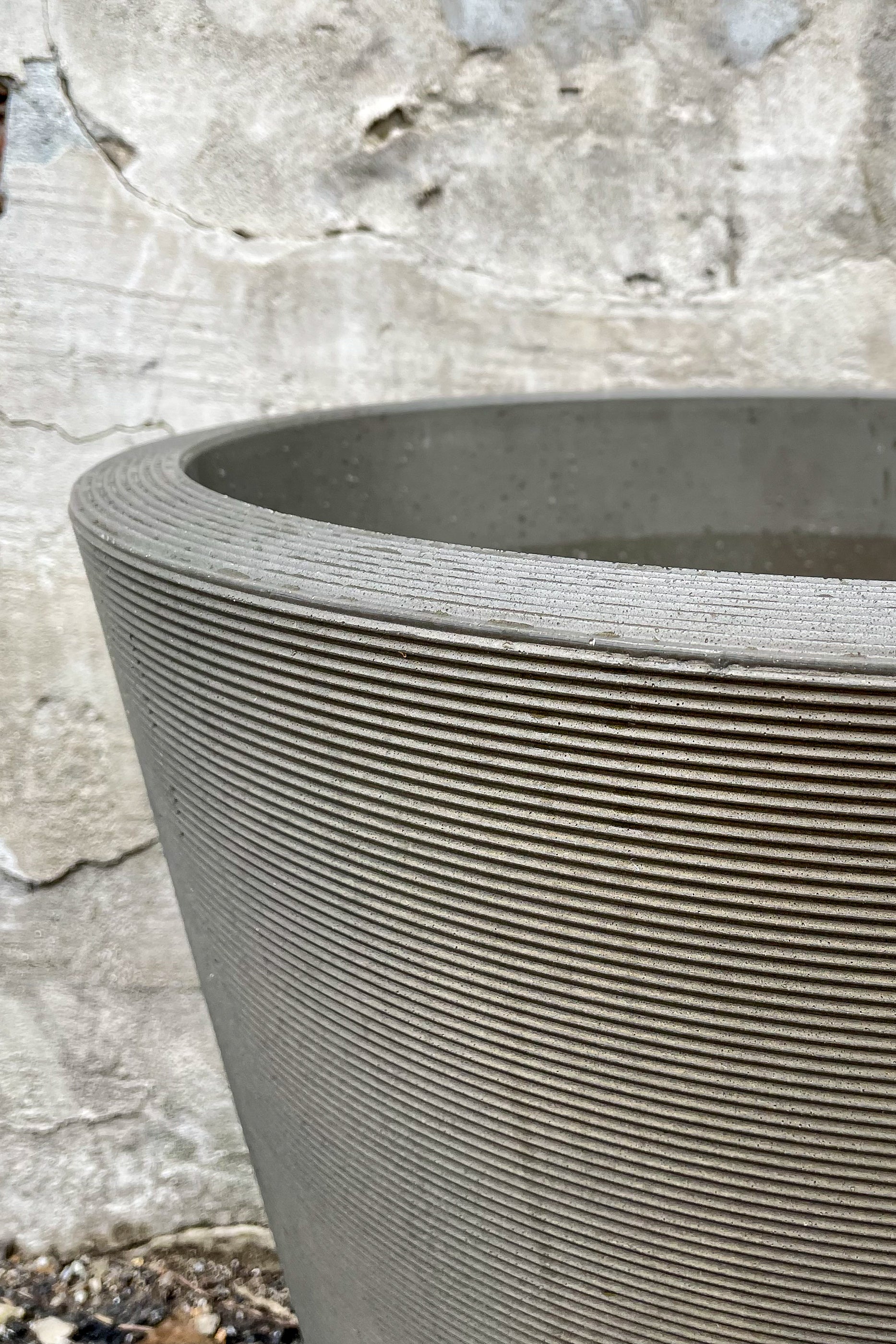 Madison Old Bronze Planter 20" by Crescent Trading in front of concrete wall