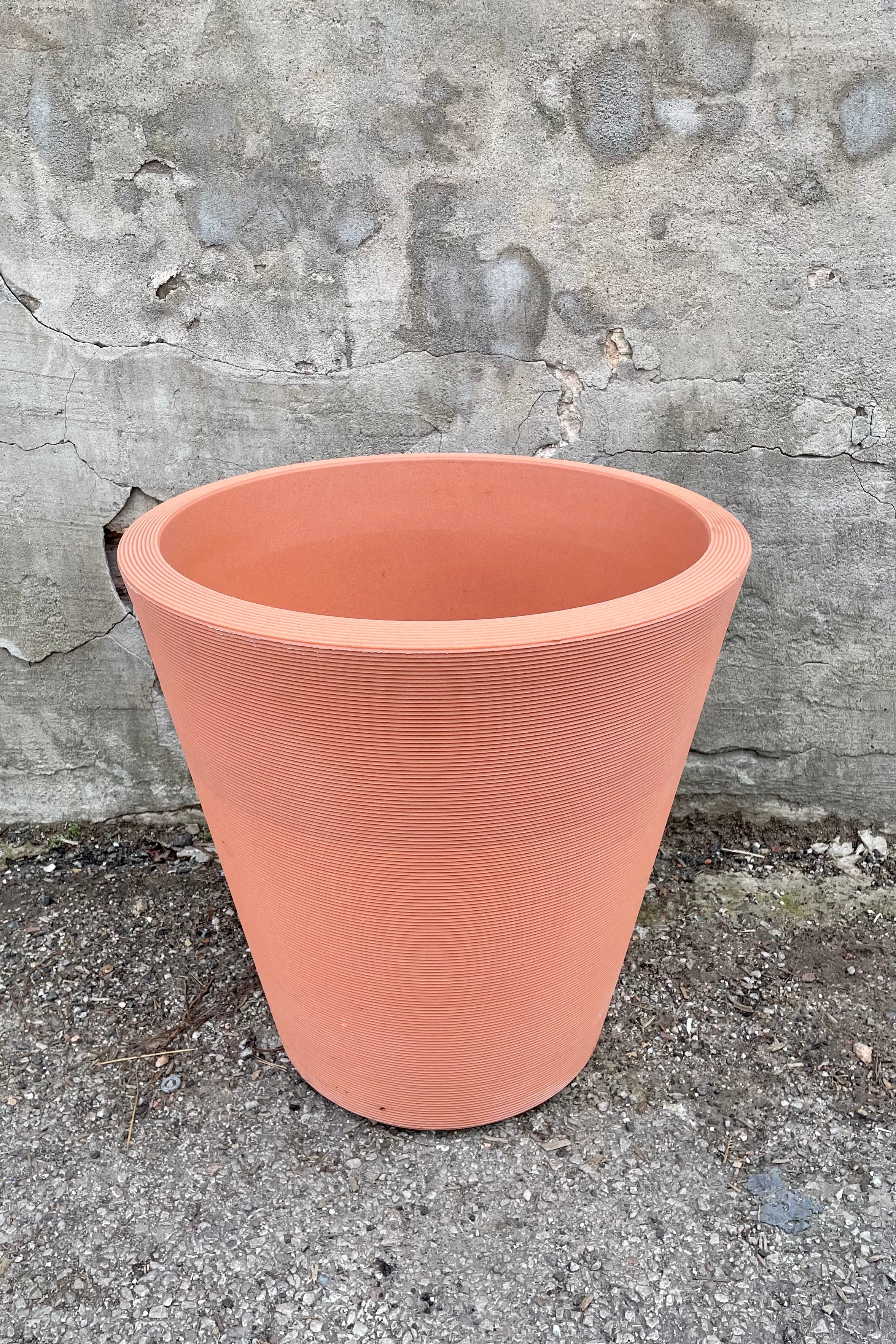 The weathered terracotta madison 20" container against a concrete wall. 