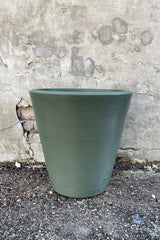 The olive 20" Madison planter against a concrete wall. 