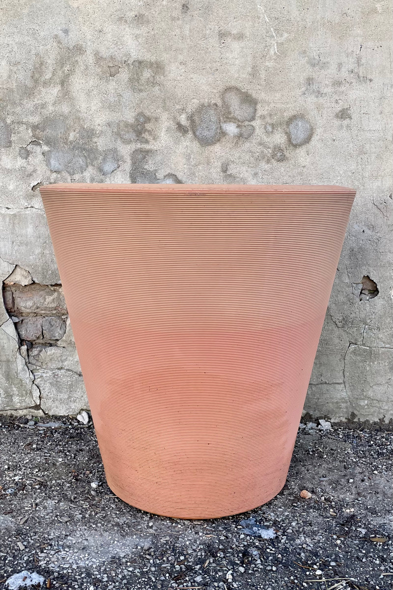 26" weathered terracotta 26" Madison planter in front of a concrete wall. 