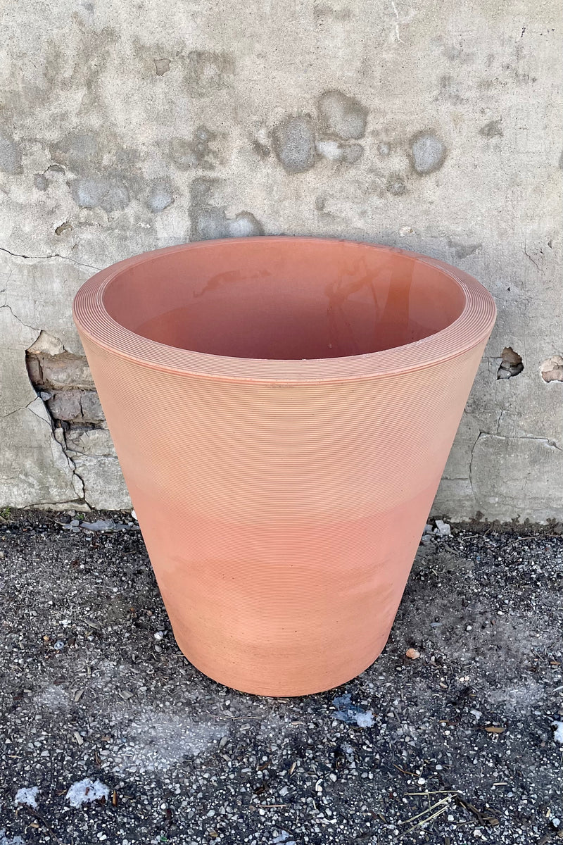26" weathered terracotta 26" Madison planter in front of a concrete wall. 