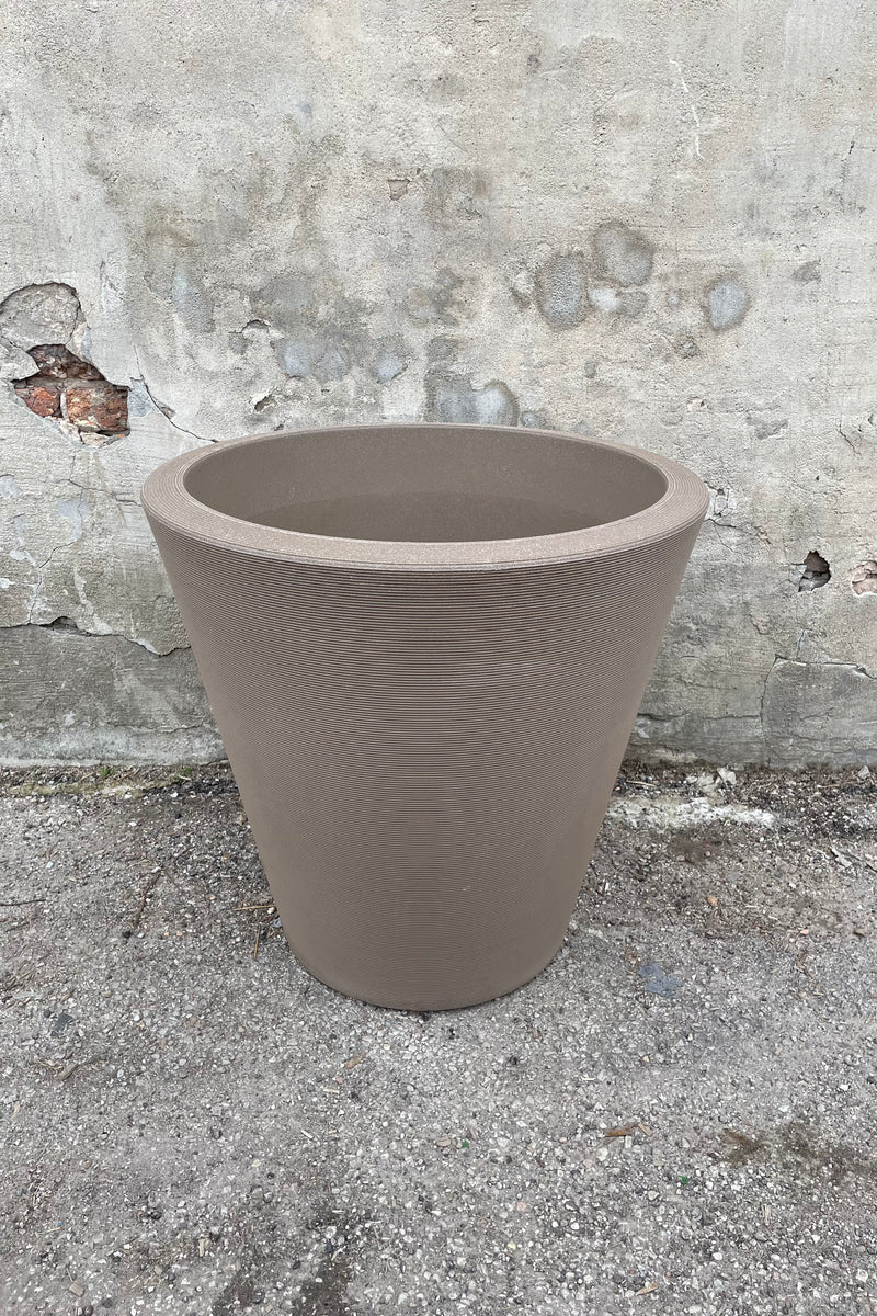 The 26" mocha Madison planter shown from the front and top against against a concrete wall. 